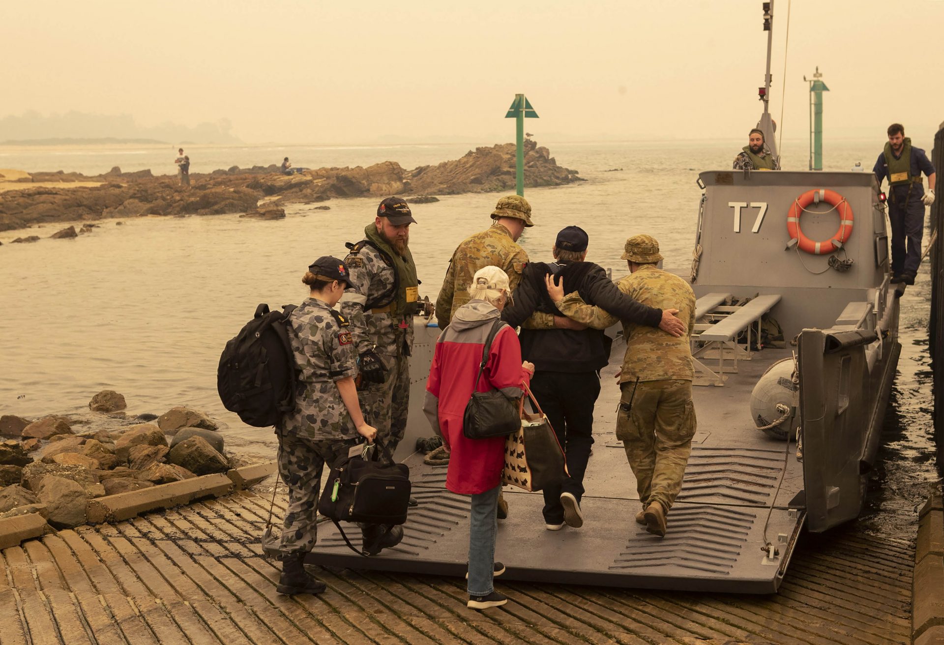 In this photo released by the Australian Department of Defense, evacuees board landing craft to be ferried out to the navy's HMAS Choules, Friday, Jan. 3, 2020, in Mallacoota, Victoria, Australia. Navy ships plucked hundreds of people from beaches and tens of thousands were urged to flee before hot weather and strong winds in the forecast worsen Australia's already-devastating wildfires.