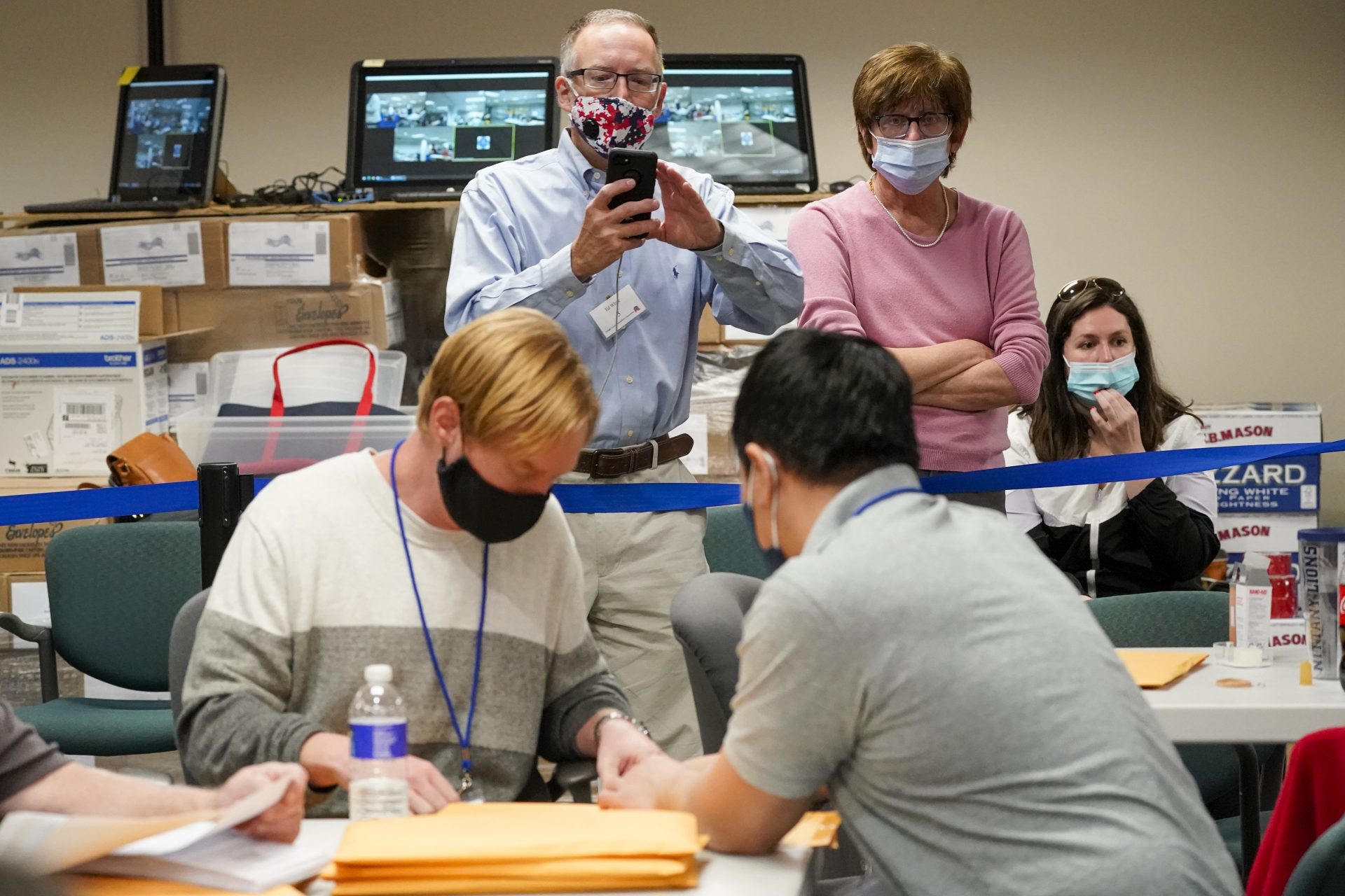 Republican canvas observer Ed White, center, and Democratic canvas observer Janne Kelhart, watch as Lehigh County workers count ballots as vote counting in the general election continues, Friday, Nov. 6, 2020, in Allentown, Pa.