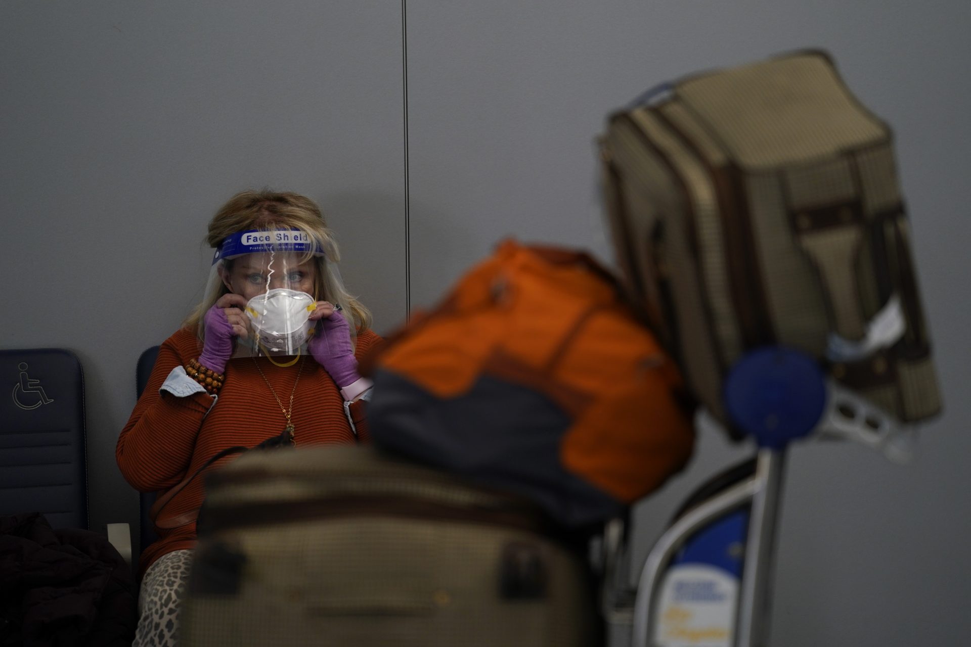 A traveler adjusts her mask while waiting to check in for her flight at the Los Angeles International Airport in Los Angeles, Monday, Nov. 23, 2020. About 1 million Americans a day packed airports and planes over the weekend even as coronavirus deaths surged across the U.S. and public health experts begged people to stay home and avoid big Thanksgiving gatherings.