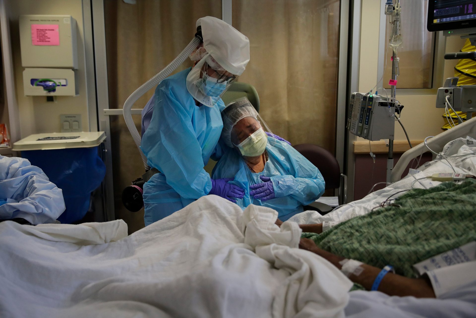 FILE PHOTO: In this July 31, 2020, file photo, Romelia Navarro, right, is comforted by nurse Michele Younkin, left, as she weeps while sitting at the bedside of her dying husband, Antonio Navarro, in St. Jude Medical Center's COVID-19 unit in Fullerton, Calif. Antonio was Younkin's first COVID-19 patient to pass on her watch.