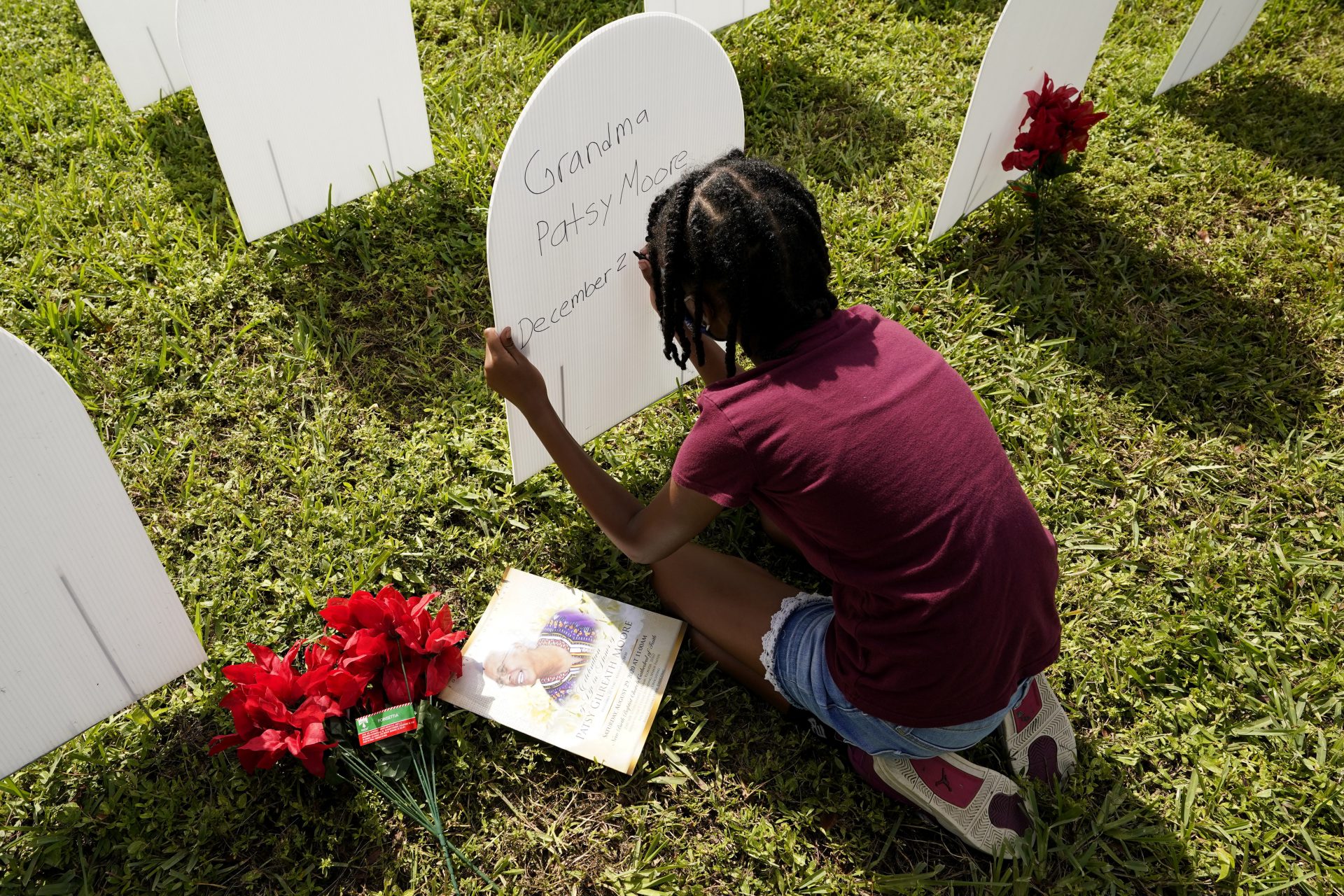 In this Nov. 24, 2020, file photo, Kyla Harris, 10, writes a tribute to her grandmother Patsy Gilreath Moore, who died at age 79 of COVID-19, at a symbolic cemetery created to remember and honor lives lost to COVID-19 in the Liberty City neighborhood of Miami. As officials met to discuss approval of a COVID-19 vaccine on Thursday, Dec. 10, the number of coronavirus deaths has grown bleaker than ever.