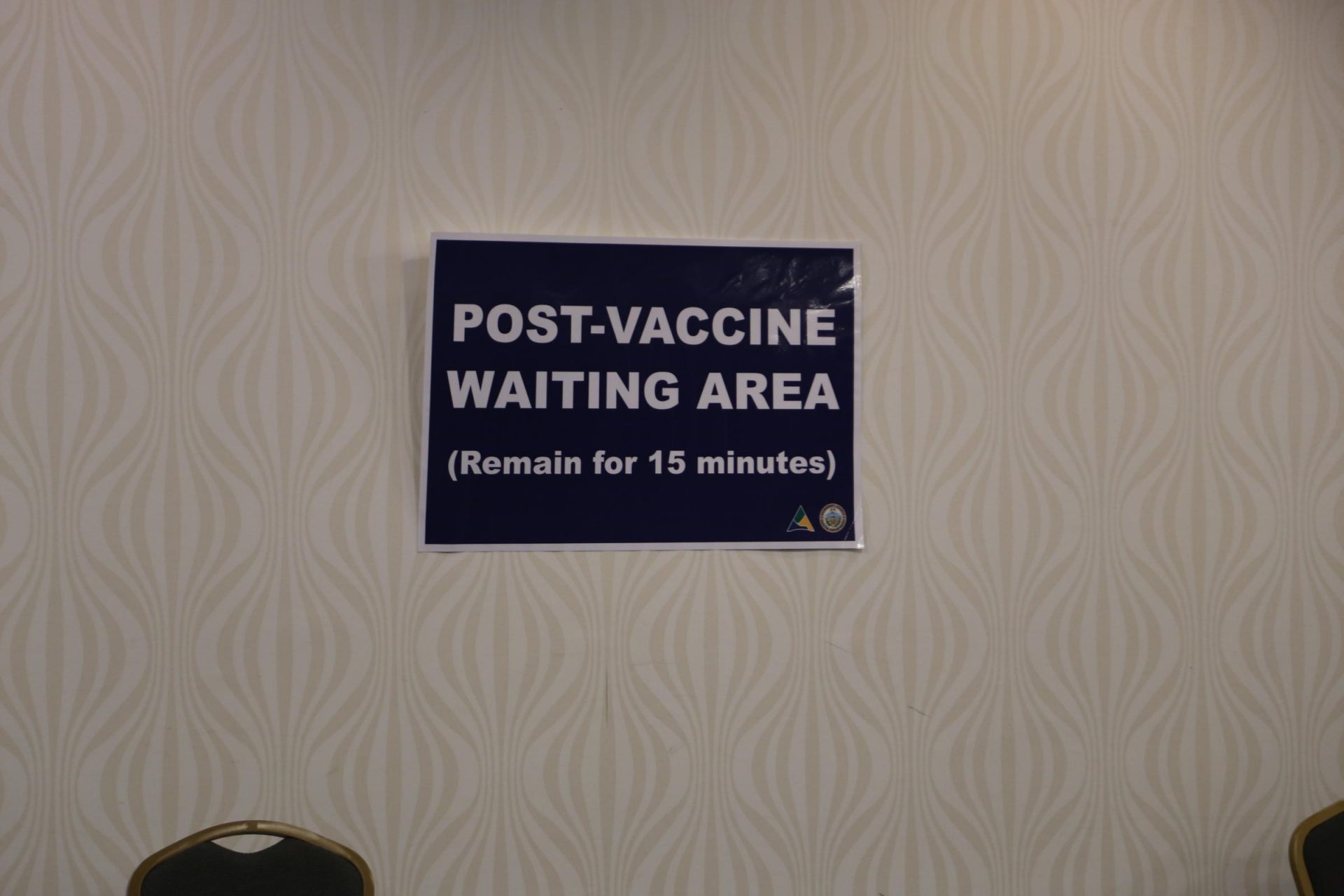 A sign marks the waiting area for people who received a COVID-19 vaccine. The 15-minute waiting period is a precaution because some people who received initial doses of the vaccine developed allergic reactions.