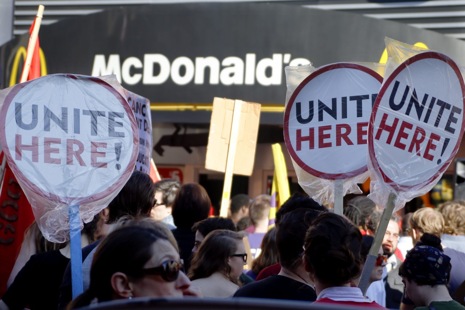 FILE PHOTO: Union organizers, students, and supporters for a $15 an hour wage wave their signs during a stop in front of a McDonalds restaurant as they march through the Oakland section of Pittsburgh, Thursday, April 14, 2016.