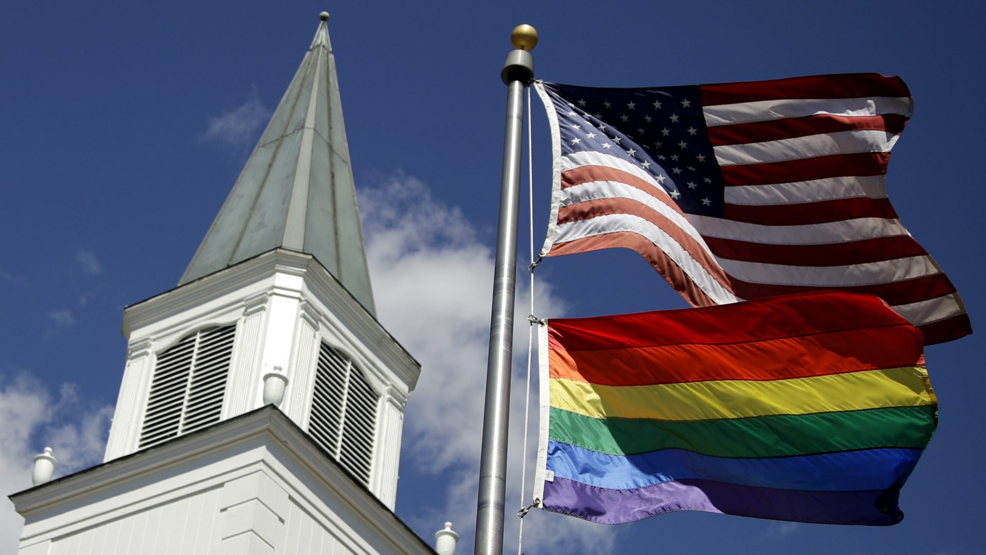 A rainbow gay pride flag flies below the U.S. flag last year in front of the Asbury United Methodist Church in Prairie Village, Kan.