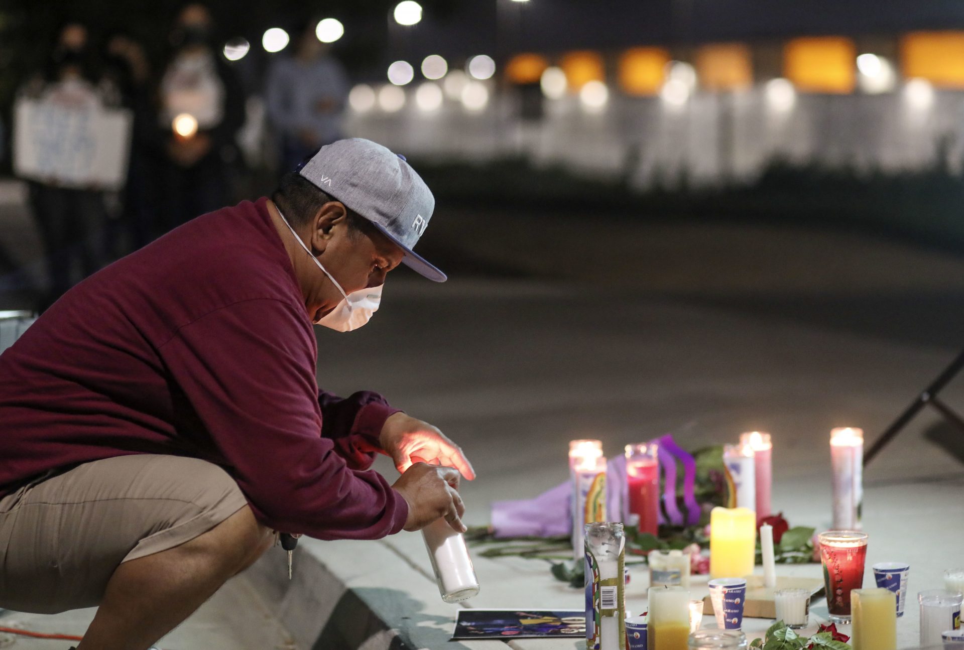 A man sets a candle outside the Otay Mesa Detention Center during a "Vigil for Carlos" on May 9 in San Diego. The vigil was held to commemorate Carlos Ernesto Escobar Mejia, who died of COVID-19-related symptoms at the detention center.