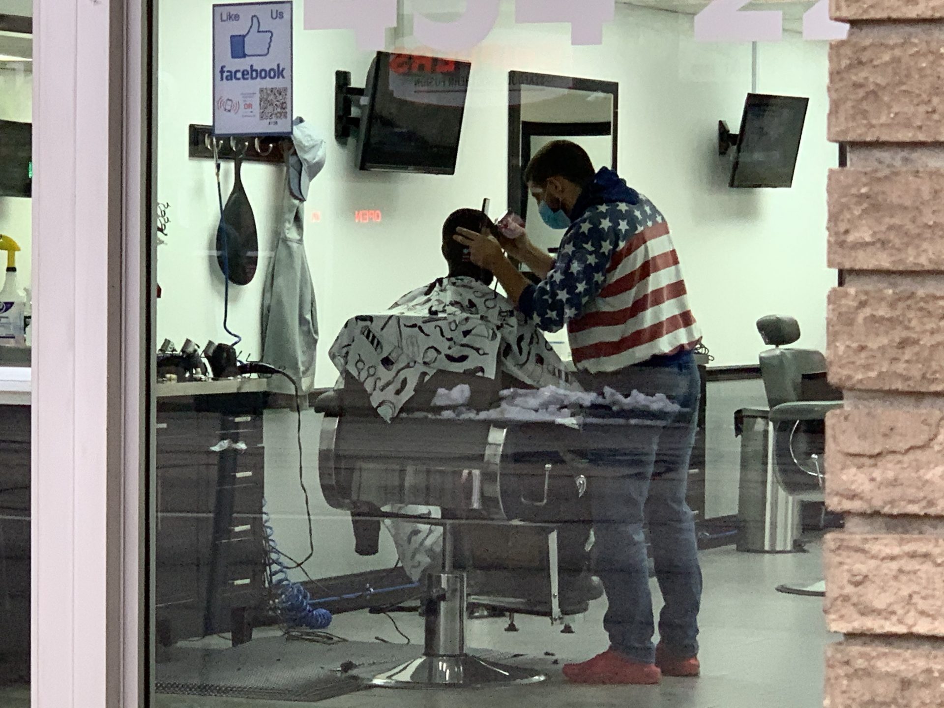 A masked barber gives a customer a trim at Russo's Barber Shop in Erie on Dec. 8, 2020.