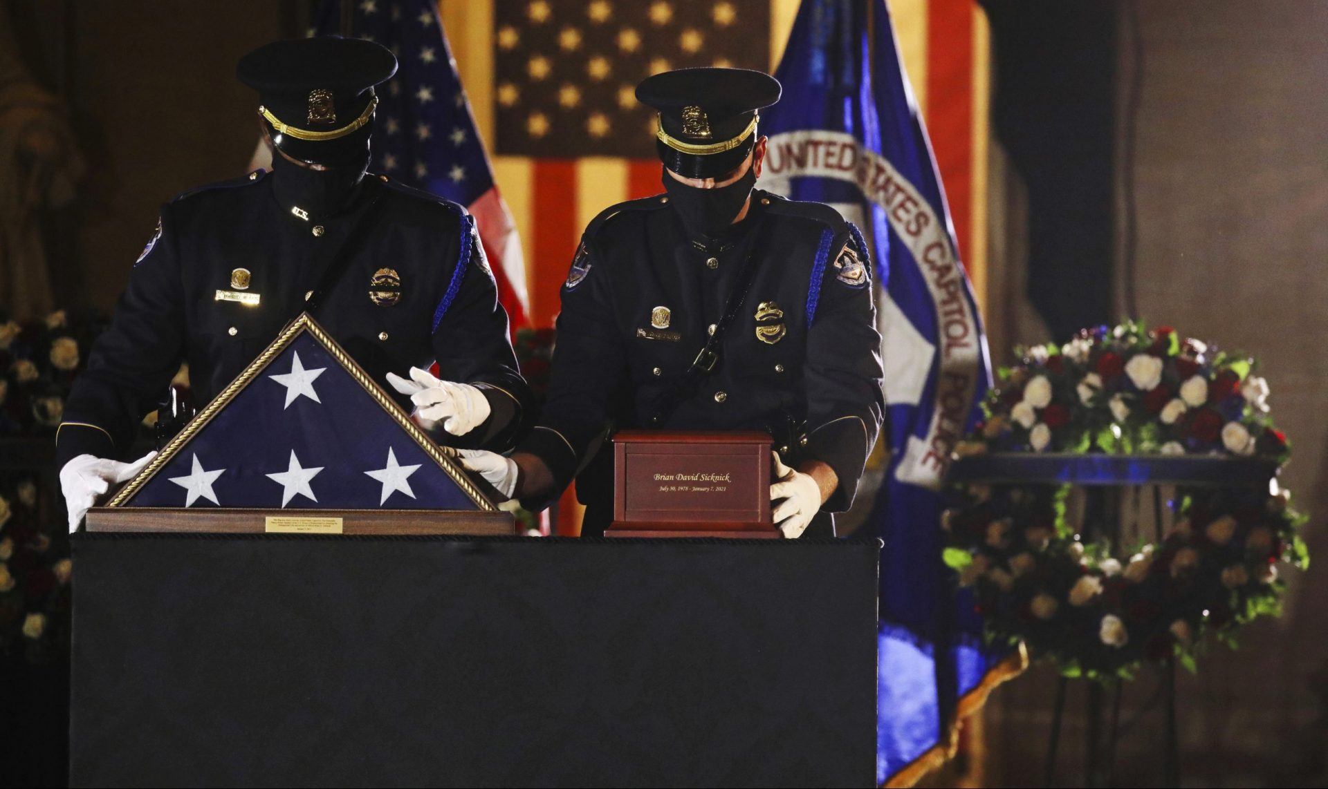 An honor guard places an urn with the cremated remains of U.S. Capitol Police officer Brian Sicknick and folded flag on a black-draped table at center of the Capitol Rotunda to lie in honor Tuesday, Feb. 2, 2021, in Washington.