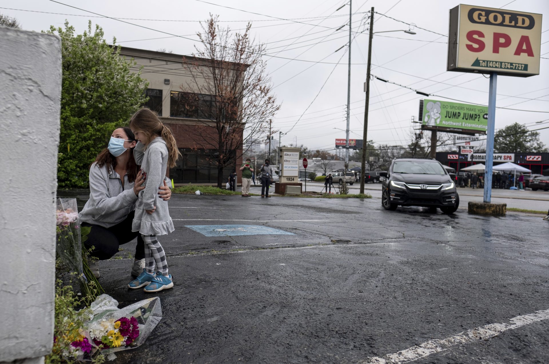 Mallory Rahman and her daughter Zara Rahman, 4, who live nearby, pause after bringing flowers to the Gold Spa massage parlor in Atlanta, Wednesday afternoon, March 17, 2021, the day after eight people were killed at three massage spas in the Atlanta area. Authorities have arrested 21-year-old Robert Aaron Long in the shootings at massage parlors in Atlanta and one in Cherokee County.
