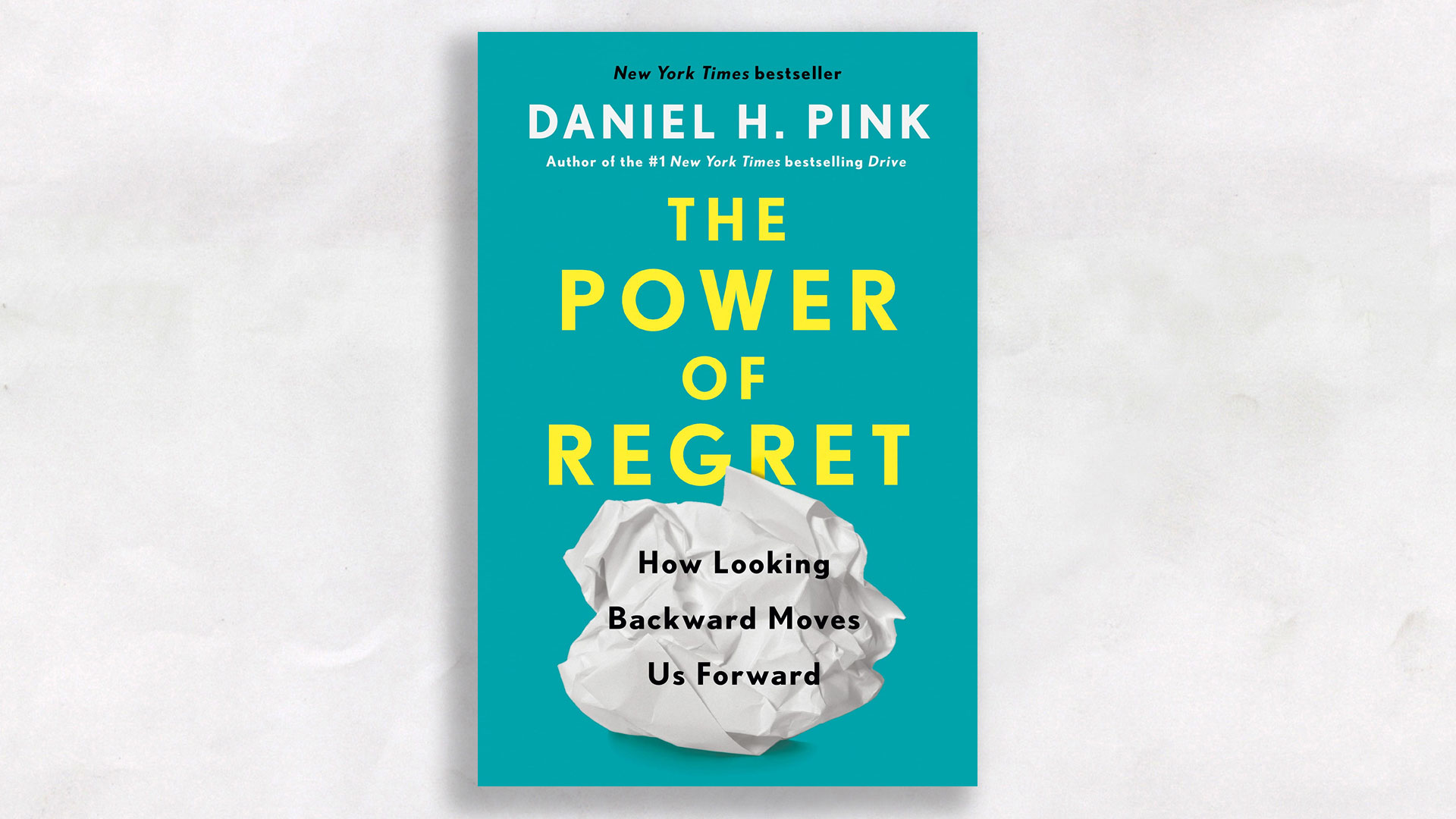 book on crumple white paper background: The Power of Regret by Daniel H. Pink.
