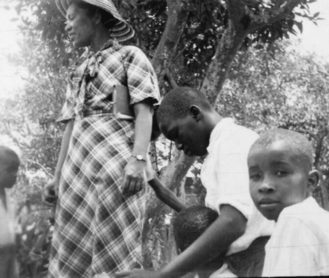 Black and white photo showing Zora Neale Hurston plays with children in Eastonville, FL.