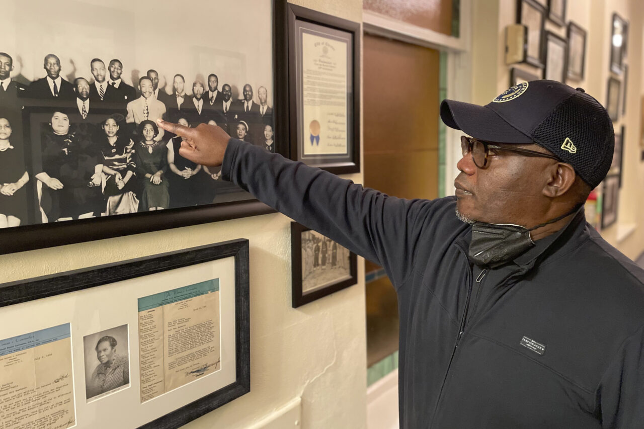 On Saturday, Oct. 7, 2023, Calvary Baptist Church Pastor Keith Dickens points to a photo of Martin Luther King Jr, who attended his church when he was a seminarian in Chester, Pa. Dickens says the historic church's location near Philadelphia Union's Subaru Park has become "a blessing" because his congregation has transformed its parking lot into game-day fundraisers and is able to connect with fans who are learning more about the historic church where Martin Luther King Jr attended as a seminarian. (AP Photo/Luis Andres Henao)