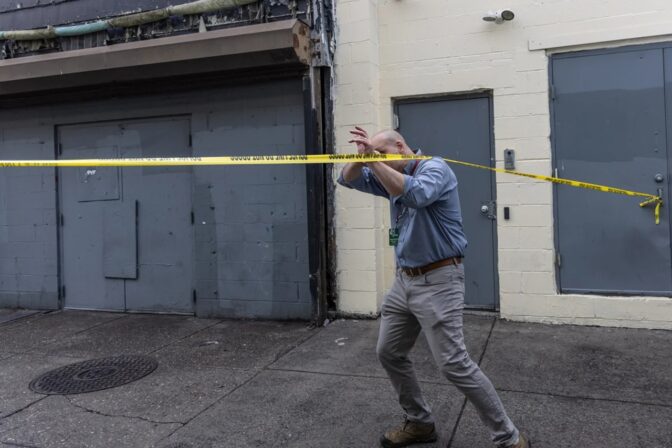 Kevin Moore, executive director of Courage Medicine Health Center, ducks under police tape at East Orleans Street and Kensington Avenue in Philadelphia’s Kensington neighborhood during the city’s sweep of Kensington Avenue on May 8, 2024. (Kimberly Paynter/WHYY)