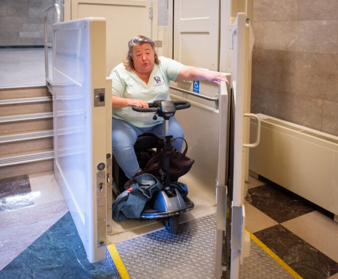 Pam Auer, director of advocacy at Center for Independent Living of Central Pennsylvania, exits a chair lift near Senate hearing rooms inside the North Office Building In the Pennsylvania Capitol complex in Harrisburg Tuesday, June 4, 2024.