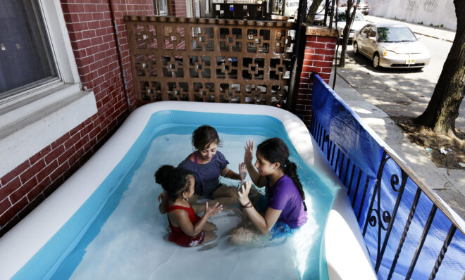 Karina, 11, Amarilys, 9 and Laylana, 3, play patty-cake in an inflatable pool on the front porch as they keep cool in the West Kensington neighborhood of Philadelphia, Monday July 2, 2018. The National Weather Service has issued an excessive heat warning through Tuesday in the Philadelphia area with oppressive temperatures expect to last through the Fourth of July holiday. (AP Photo/Jacqueline Larma)