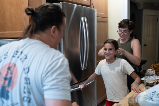 Andrew DiDonato (left) places his hair into a bun while his wife Ashley (right) does the same to their daughter Rosalie in their home in Philadelphia, Pennsylvania on July 22, 2024.