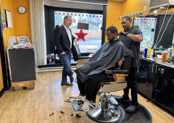 Justin Douglas talks with Marcus Clark and Bernard Dow in his Super Star Status Barber shop in Harrisburg, Pa.'s Allison Hill neighborhood on May 13, 2026.