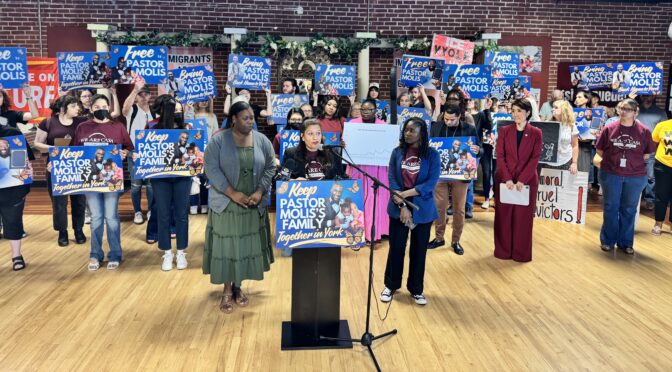 Olga Galati, deputy director for We Are CASA Pennsylvania, stands with the wife of a detained immigrant and pastor, along with over two dozen supporters.